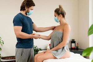 Man manual therapist wearing prevention mask is working with a woman client photo