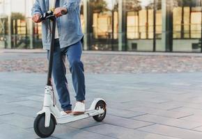 hombre montando su e-scooter en la calle de la ciudad foto