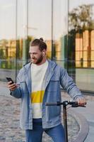 Man with e-scooter using  scooter-sharing system application on his smartphone photo