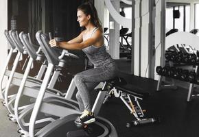 Cheerful woman is cycling on stationary bike during her cardio workout in the gym photo