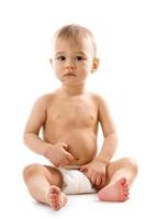 Curious healthy little boy in diaper sitting and looking. photo