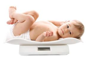 Weighing of a little boy in diaper lying on scales. photo