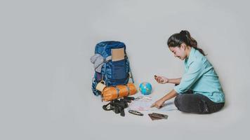 Tourist planning vacation with the help of world map with other travel accessories around. Woman traveler with suitcase on white background. Concept travel backpack photo