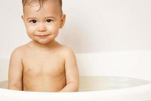 Smiling little boy taking a bath in warm water. photo