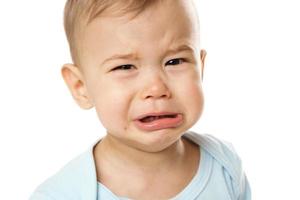 Closeuo shot of face of crying little boy in romper. photo