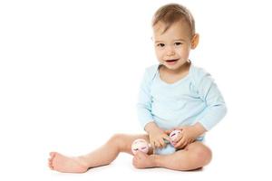 Little boy in romper sitting and playing with plastic rattle. photo