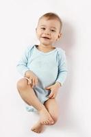 Little boy in romper lying on back and smiling. photo