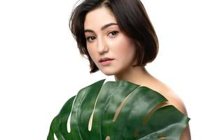 Portrait of young beautiful brunette woman with a monstera deliciosa tropical leaf photo