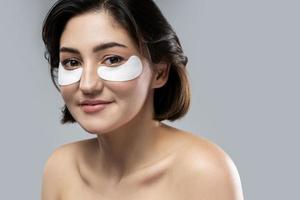 Beautiful woman with a smooth skin applying adhesive under-eyes patches for dark circles photo