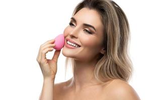 Beautiful woman with a smooth skin holding makeup sponge on white background photo