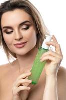 Young woman with a smooth skin holding a bottle of green cleansing gel photo