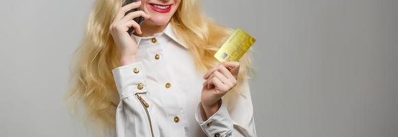 Photo of beautiful young woman isolated over white background. Looking aside holding credit card