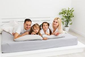 familia joven descansando juntos en la cama de los padres foto