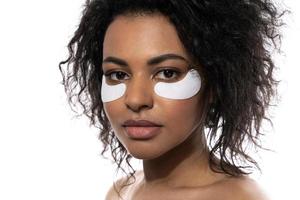 Beautiful black woman with a smooth skin applying adhesive under-eyes patches for dark circles photo