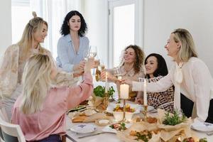 Young women friends clinking glasses at the festive table. photo