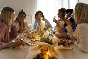Young woman friends drinking wine at the festive table. photo