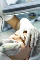 Young woman during professional permanent makeup treatment photo