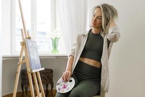 Young woman artist painting on canvas on the easel photo