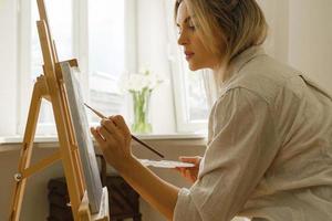 joven artista pintando sobre lienzo en el caballete foto