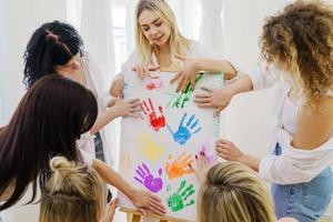 Group of women paint on canvas and drinking white wine during party at home photo