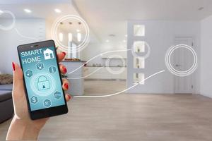 Smart home technology interface on smartphone app screen with augmented reality view of internet of things  connected objects in the apartment interior, person holding device photo