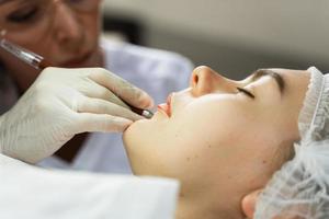 Permanent makeup artist and her client during lip blushing procedure photo