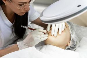 Permanent makeup artist and her client during lip blushing procedure photo