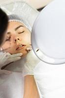 Permanent makeup artist and her client during lip blushing procedure photo