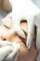 Young woman during professional permanent makeup treatment photo