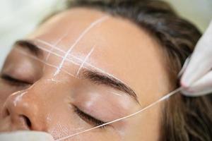 Woman during professional eyebrow mapping procedure photo
