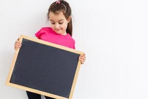 Little asian girl holding black board on white background photo