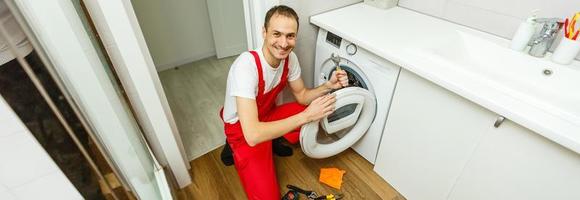 Plumber repairing washing machine photo