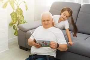niña feliz con el abuelo viendo libros de fotos en casa
