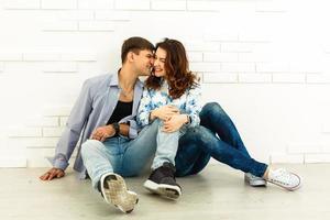 The happy man and woman sit on the background of the white wall photo