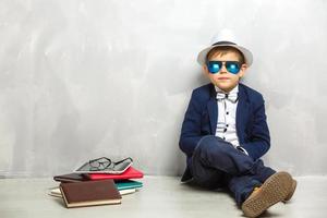 Elementary school student carrying notebooks over a gray background photo