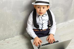 retrato del genio. niño trabajando en la computadora sentado en el suelo. estudiando. aprendizaje en línea de forma remota. escuela lejana. educación a distancia. cursos y conocimientos en línea. foto