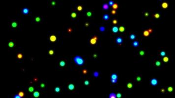 Shiny rainbow lights flying defocussed to the viewer show glowing particles in different colors on dark background as animated background glowing in the dark for festive events glamorous celebration video