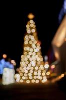 Blurred and bokeh view of Christmas tree and decorate led lighting front of shopping mall on Christmas night in urban city. photo