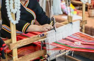 El primer plano y las manos recortadas de las damas de la tribu de las colinas de Tailandia son una demostración de tejer telas coloridas para los turistas en su aldea. foto