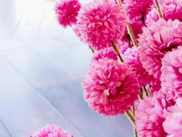 Closeup fabric pink flowers with natural sun light and wooden floor background. photo