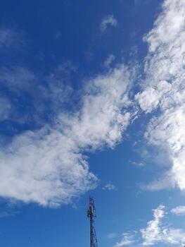 transmitter tower with a background of blue sky and clouds photo