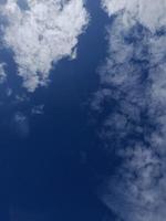 White clouds in the blue sky. Heaven and infinity. Beautiful bright blue background. Light cloudy, good weather. Curly clouds on a sunny day. photo