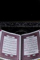 Al-Quran which is above the prayer rug with a black background photo