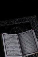 Al-Quran which is above the prayer rug with a black background photo