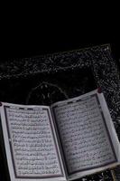 Al-Quran which is above the prayer rug with a black background photo