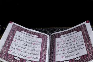 Al-Quran which is above the prayer rug with a black background photo