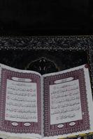 Al-Quran which is above the prayer rug with a black background photo