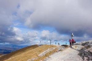 hikers on the highest mountain of lower austria near the summit cross photo