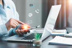 Businesswoman using phone and touching on virtual screen contact icons such as email, address, live chat, internet wifi. Contact us or Customer support hotline people connect. Connect with cyberspace. photo