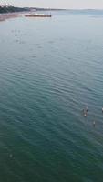 imágenes aéreas de la playa de arena británica y el océano. imágenes verticales y de estilo retrato de 4k de la playa de bournemouth con la cámara de un dron durante la puesta de sol video